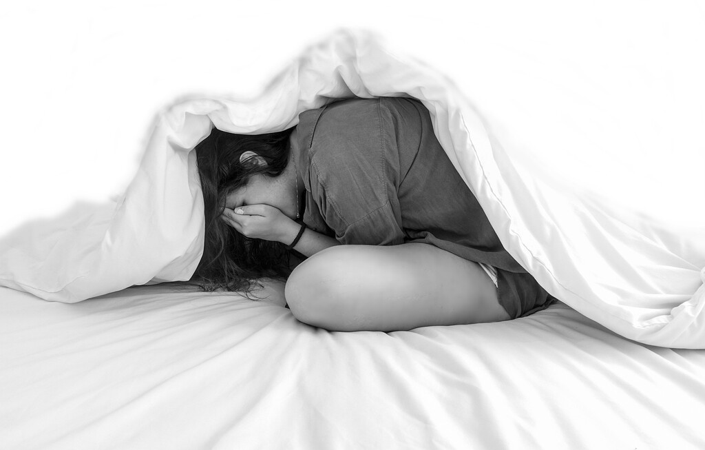 Девушка прячется под одеялом